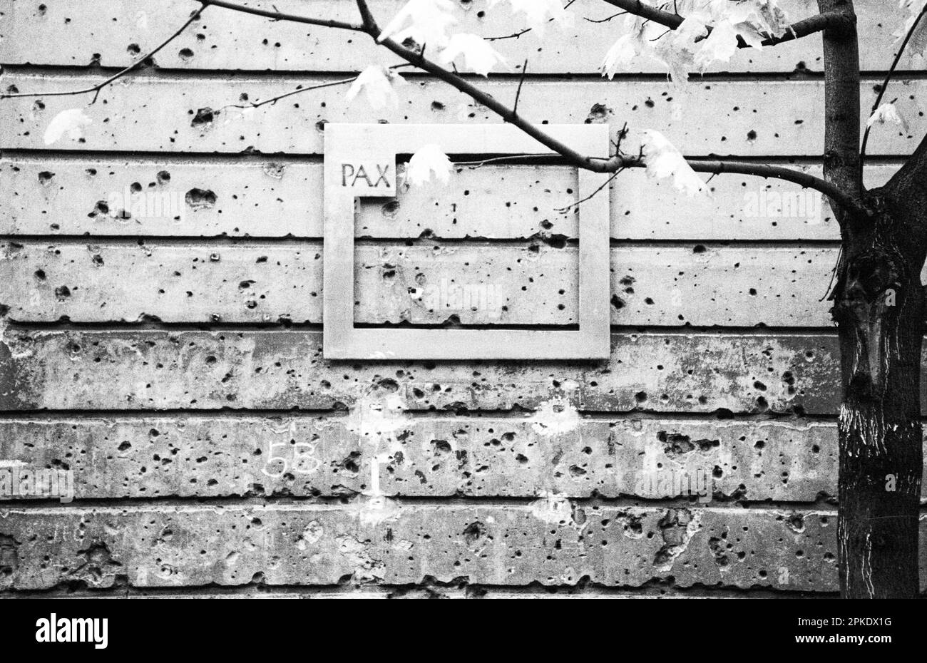 East Germany, former GDR, East Berlin, artwork, house wall with holes from bullet shots from the final battle between soviet Red Army and German Nazi soldiers in 1945 during second world war, frame with word PAX peace, historical black and white image shot on 35 mm film Stock Photo
