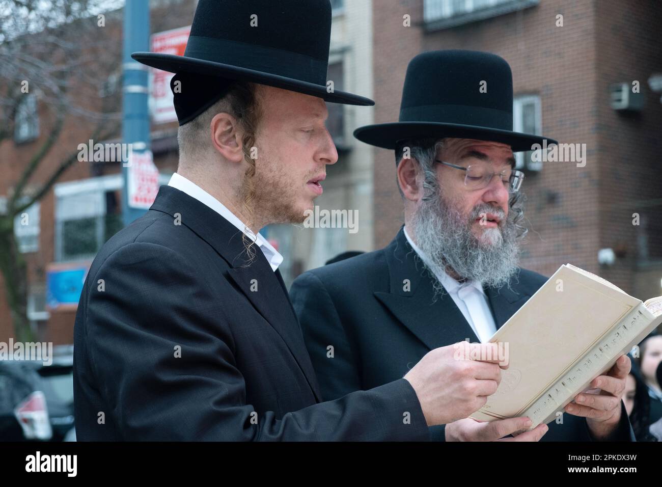 2 Hasidic jewish men sharing a prayer book at the ceremony for burning