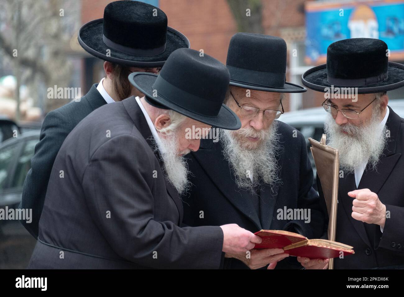 4 Hasidic jewish men sharing a prayer book at the ceremony for burning