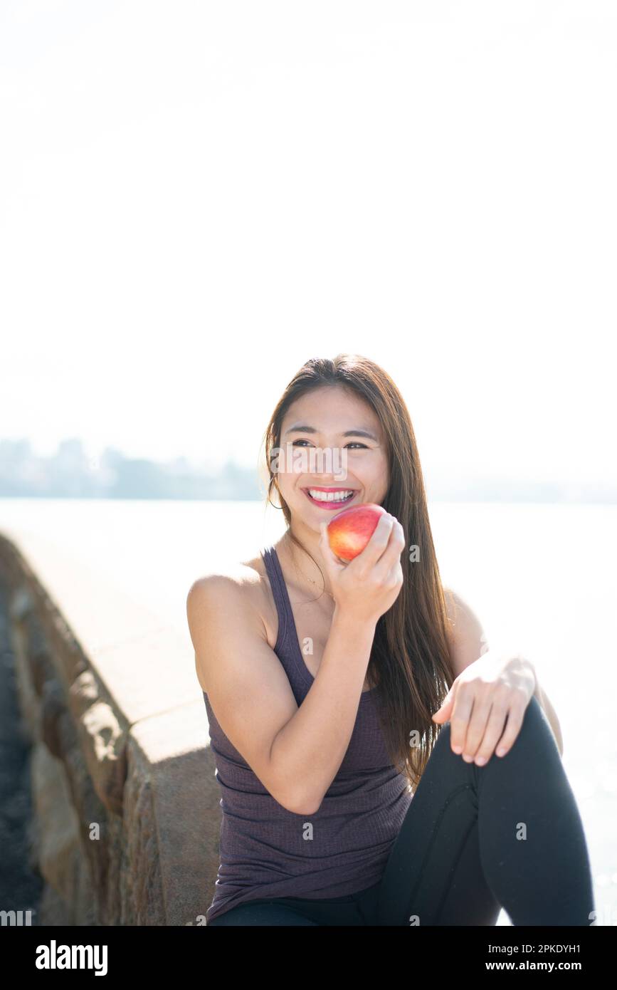 Woman eating an apple by the water Stock Photo