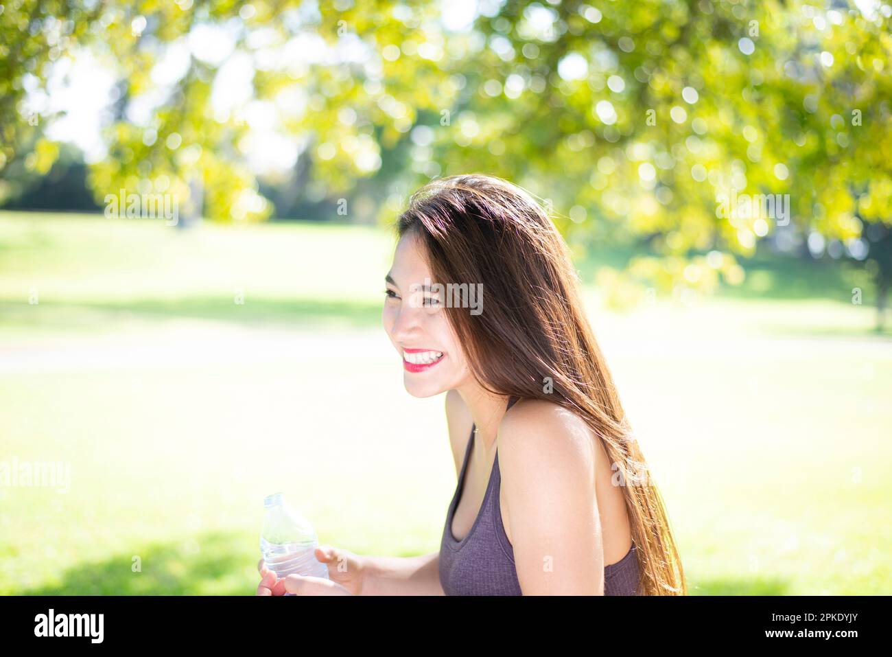 Woman laughing in park with bottle of water Stock Photo - Alamy
