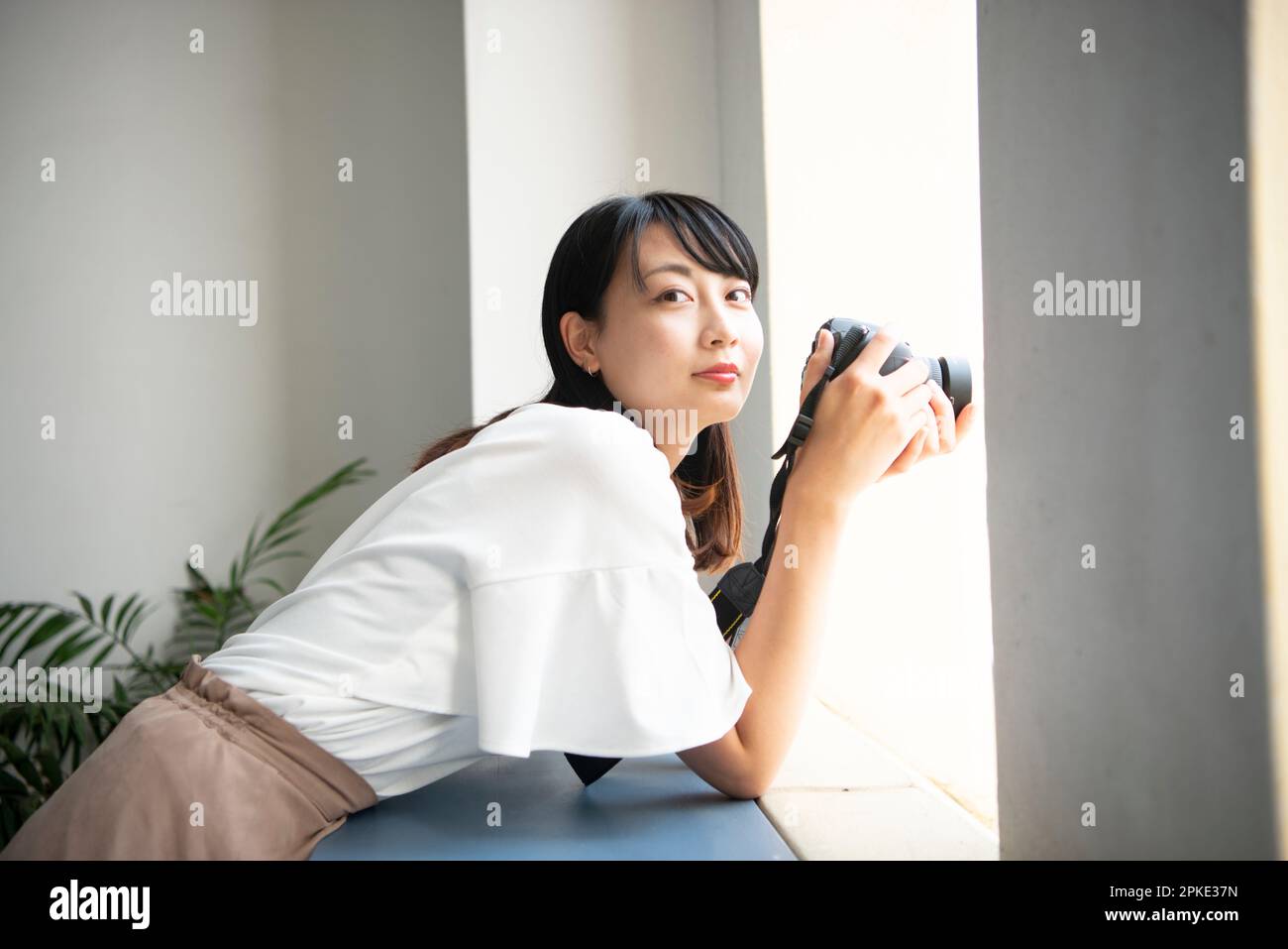 Woman holding SLR camera and looking at me Stock Photo