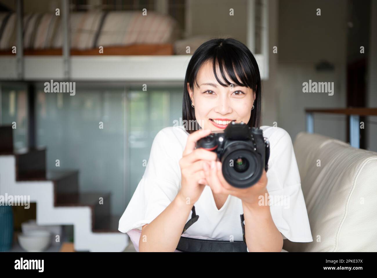 Woman holding SLR camera and smiling Stock Photo