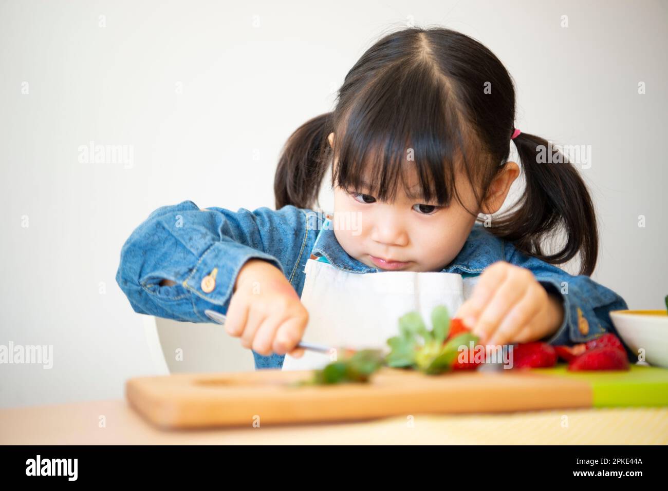 Girl seriously cutting strawberries Stock Photo