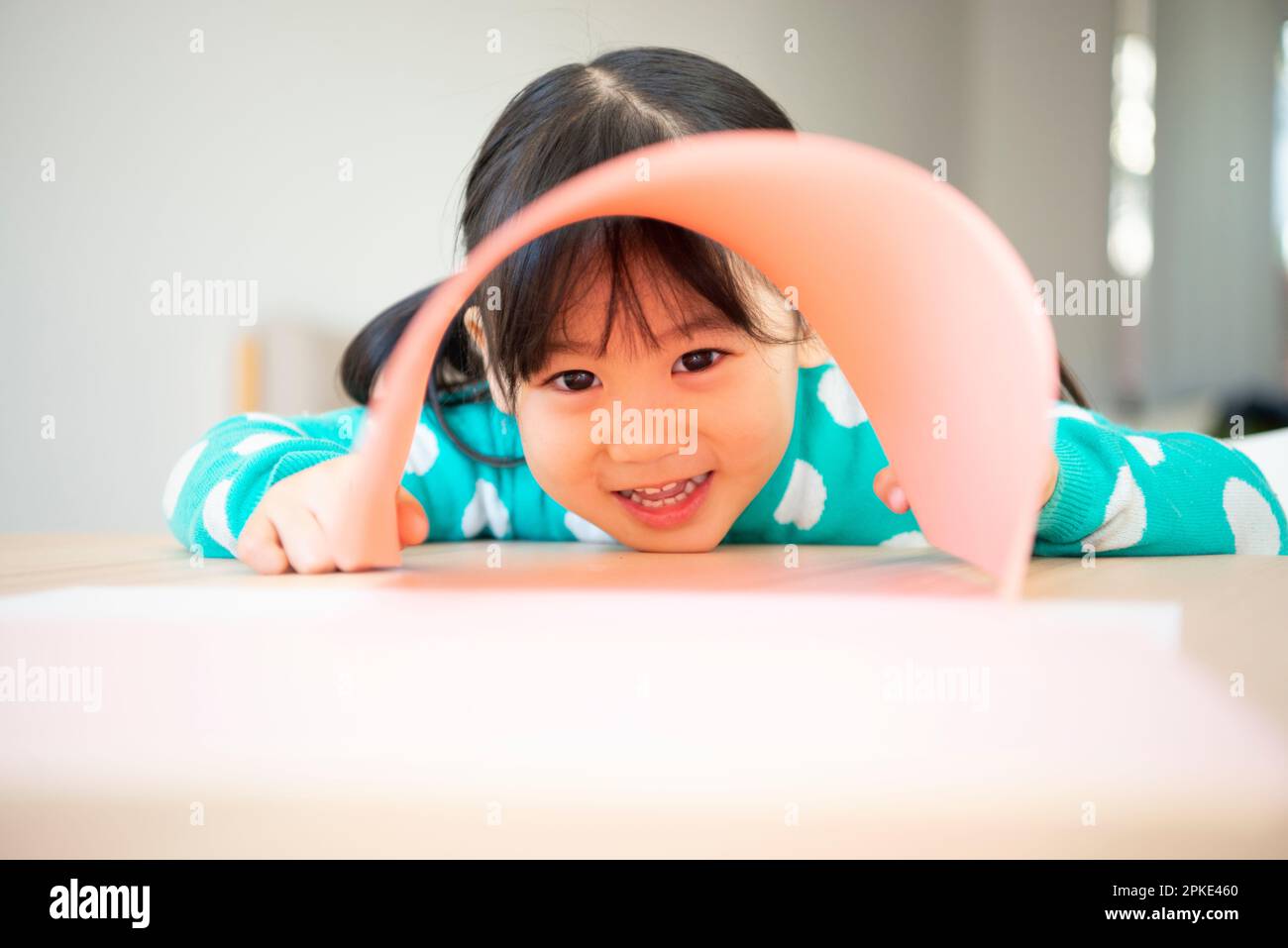 Girl peeking through a gap in the drawing paper Stock Photo