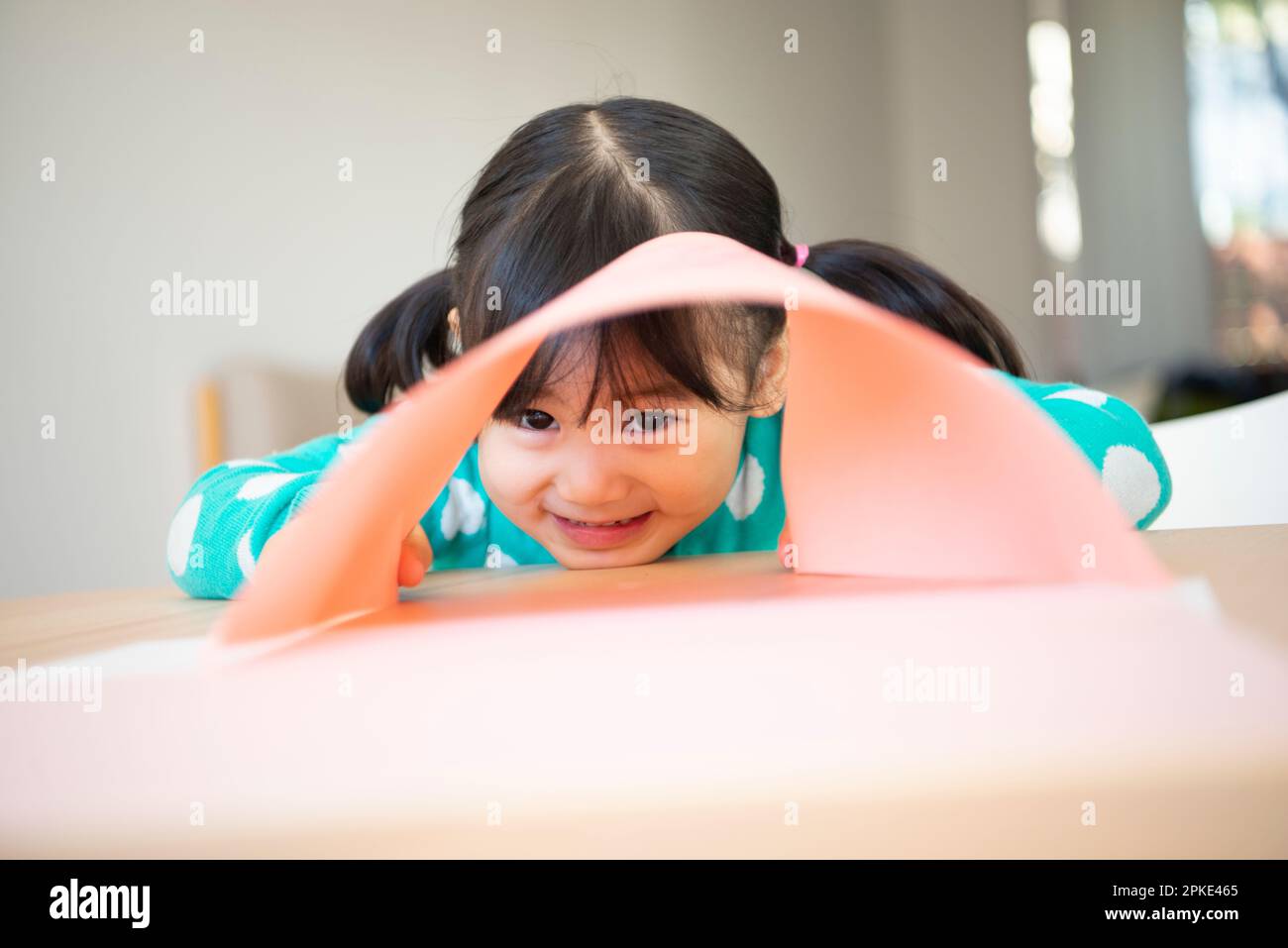 Girl peeking through a gap in the drawing paper Stock Photo