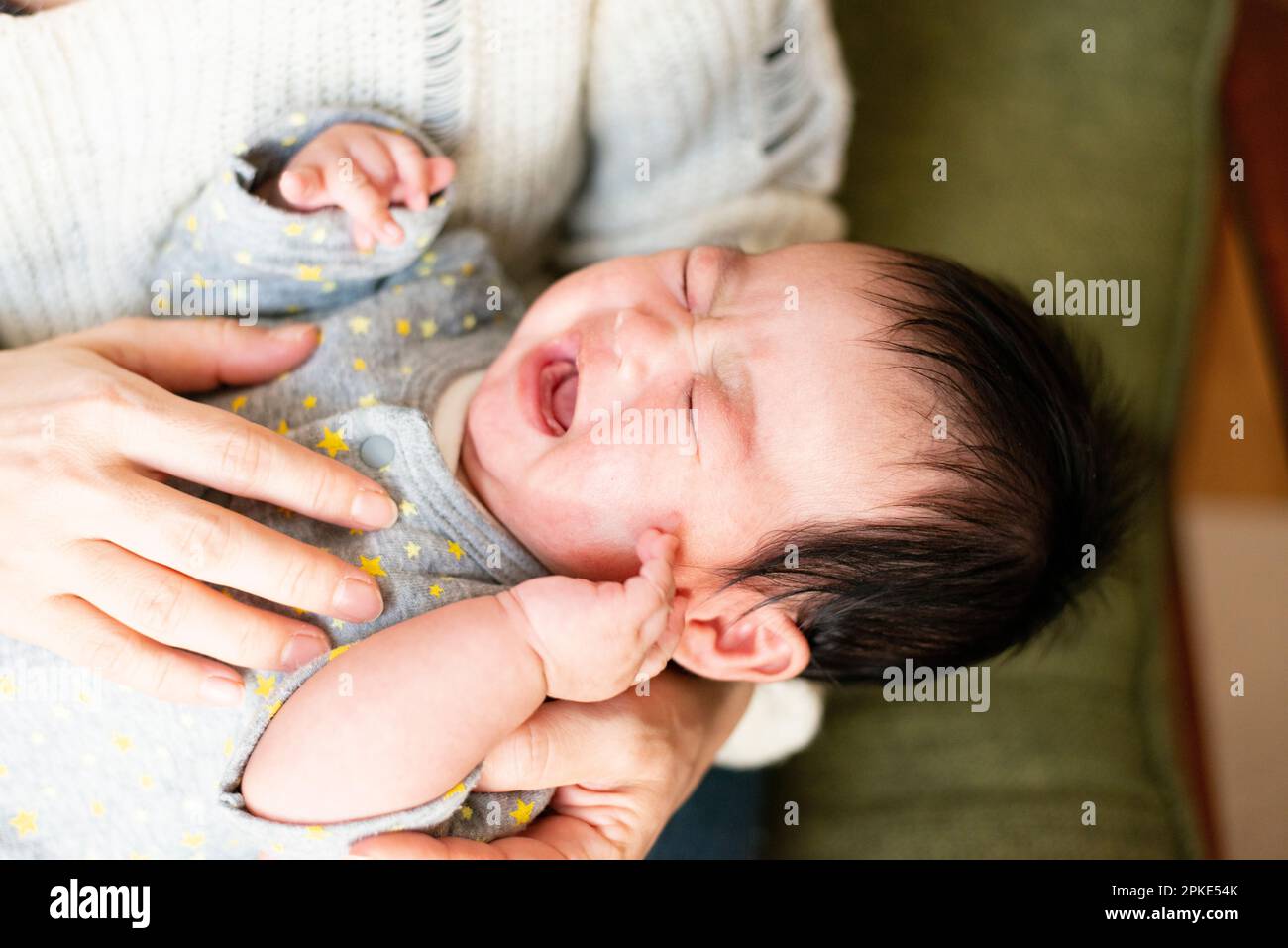 Baby crying while being carried Stock Photo