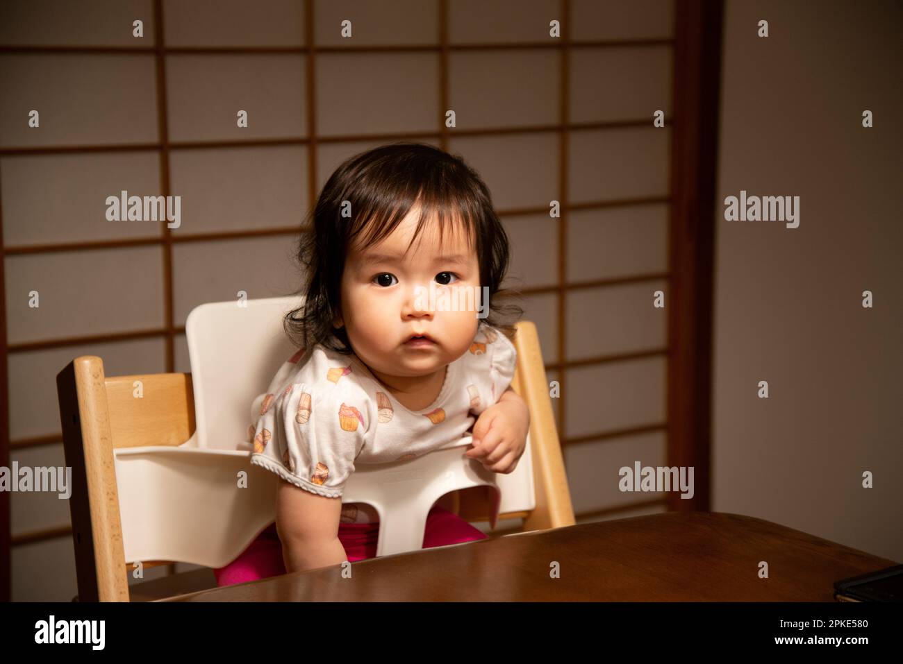 Babies sitting in highchairs looking at you Stock Photo