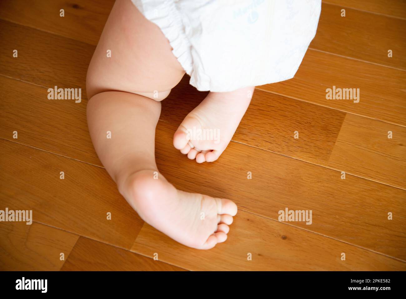 Baby's feet in diaper crawling Stock Photo