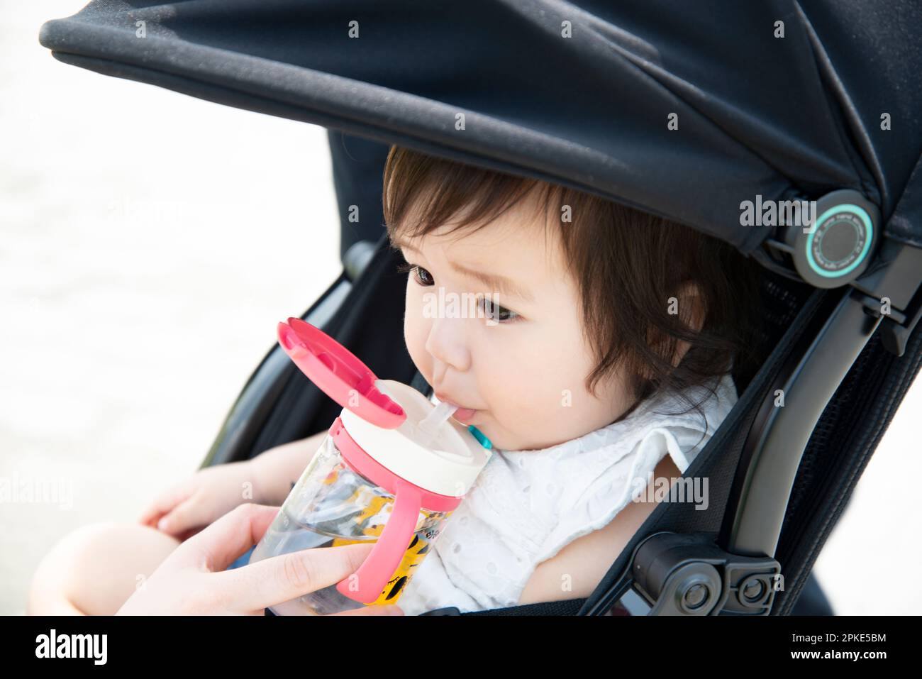 Baby sitting in stroller drinking water Stock Photo
