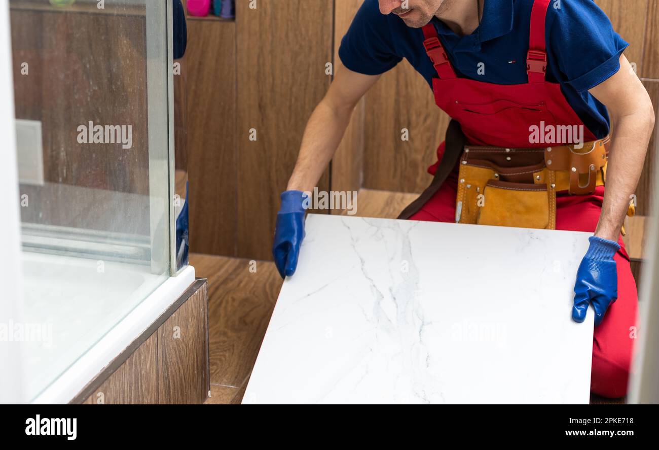 A male construction worker installs a large ceramic tile  Stock Photo