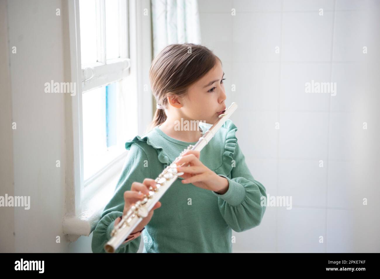 Girl playing flute by the window Stock Photo Alamy
