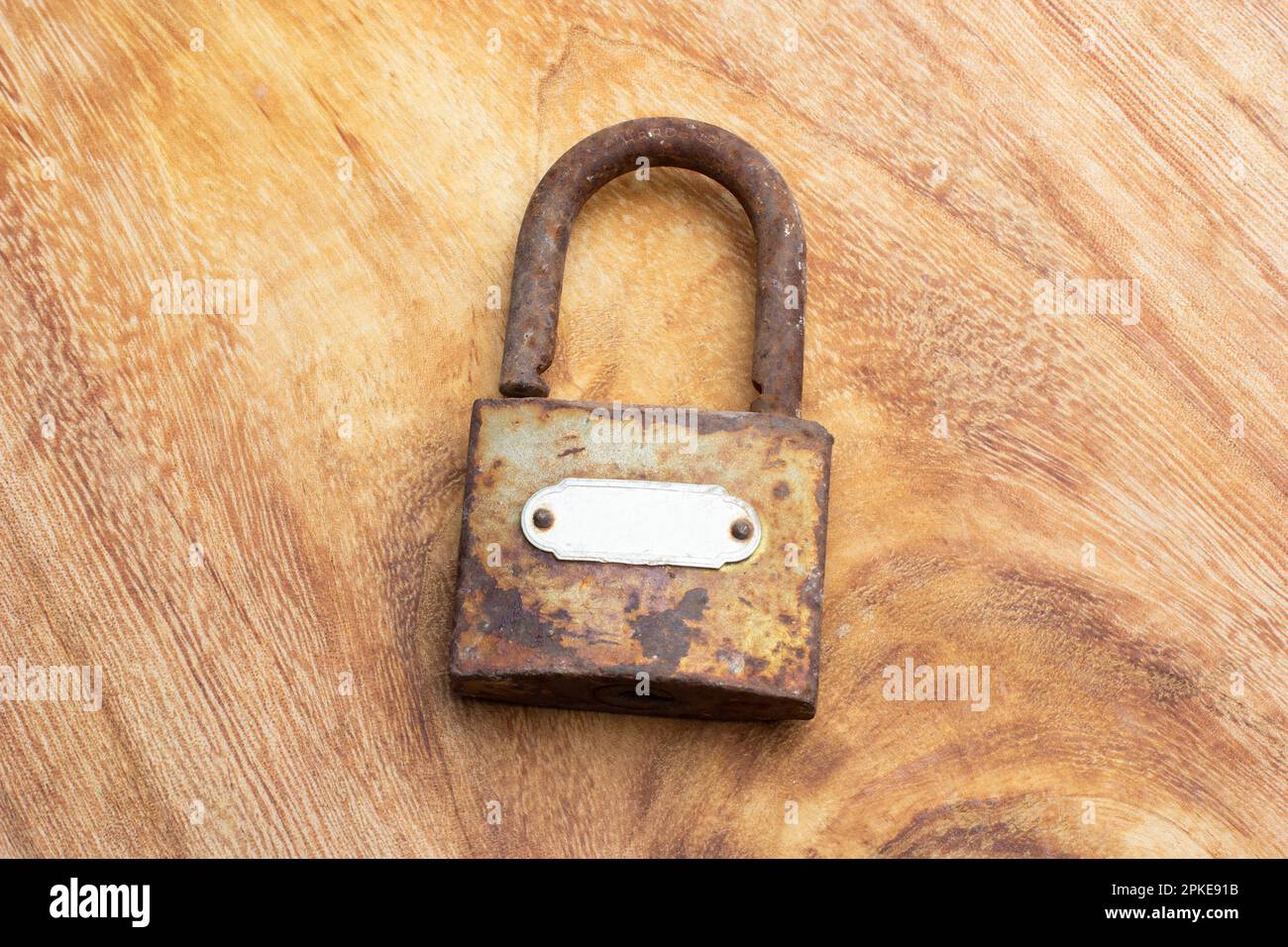 A rusty open padlock on a wooden table in a top view Stock Photo