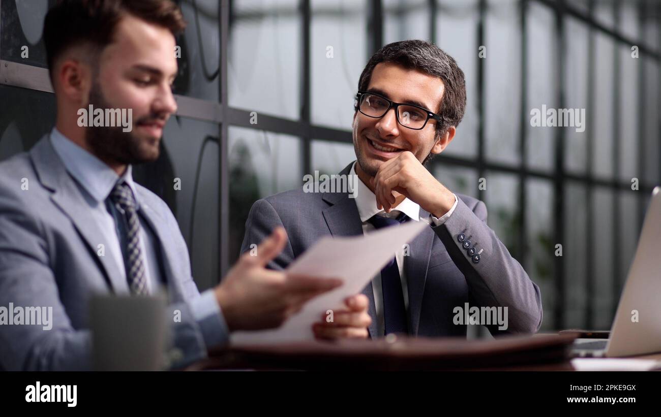 colleagues talking and sitting at table in creative agency Stock Photo