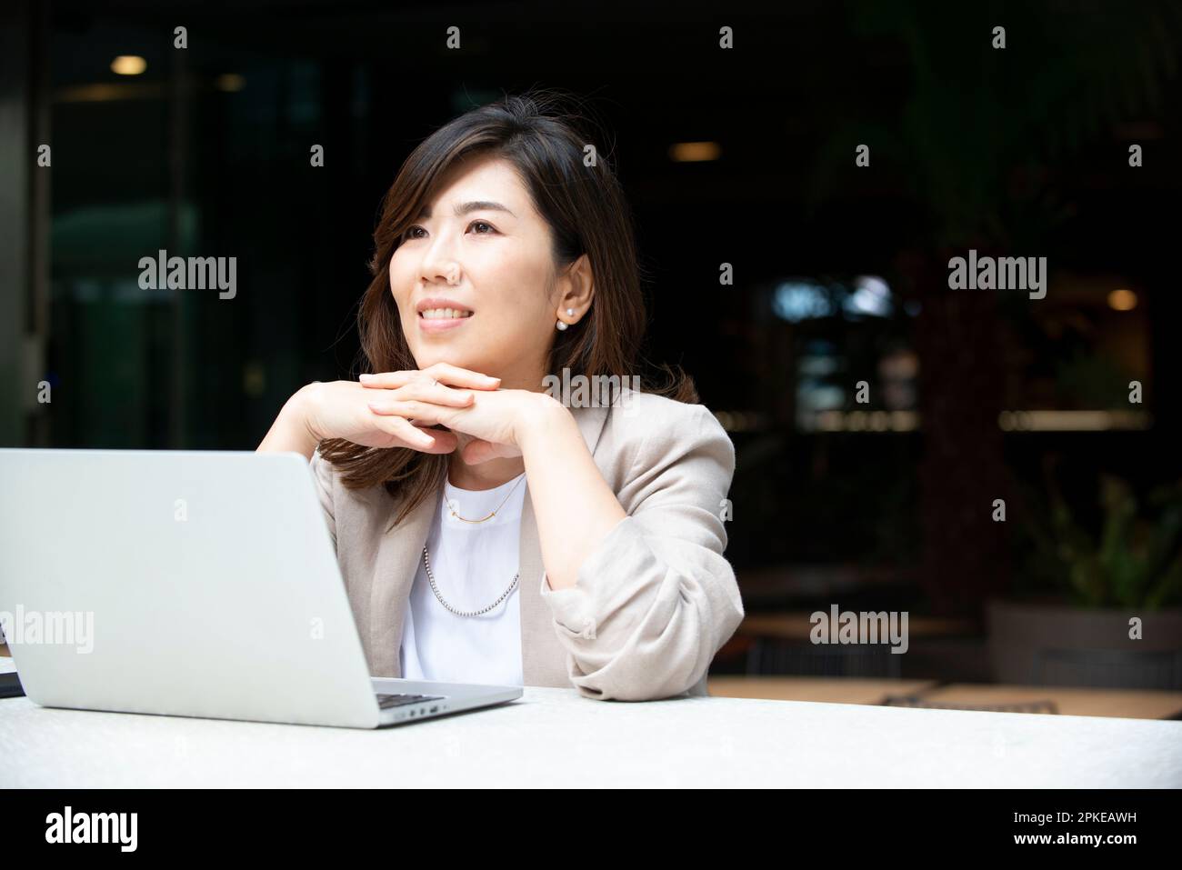 Woman thinking with computer open outside Stock Photo