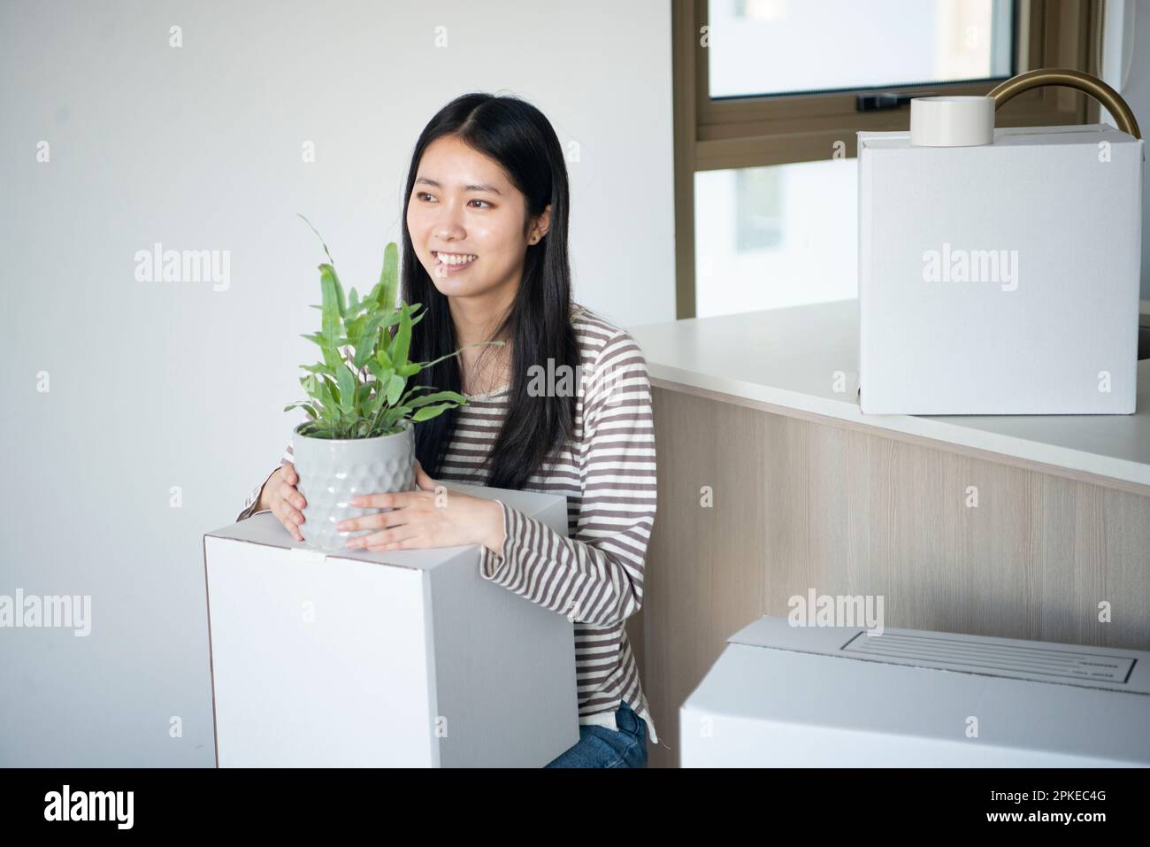 Woman holding moving cardboard and plant pot Stock Photo - Alamy