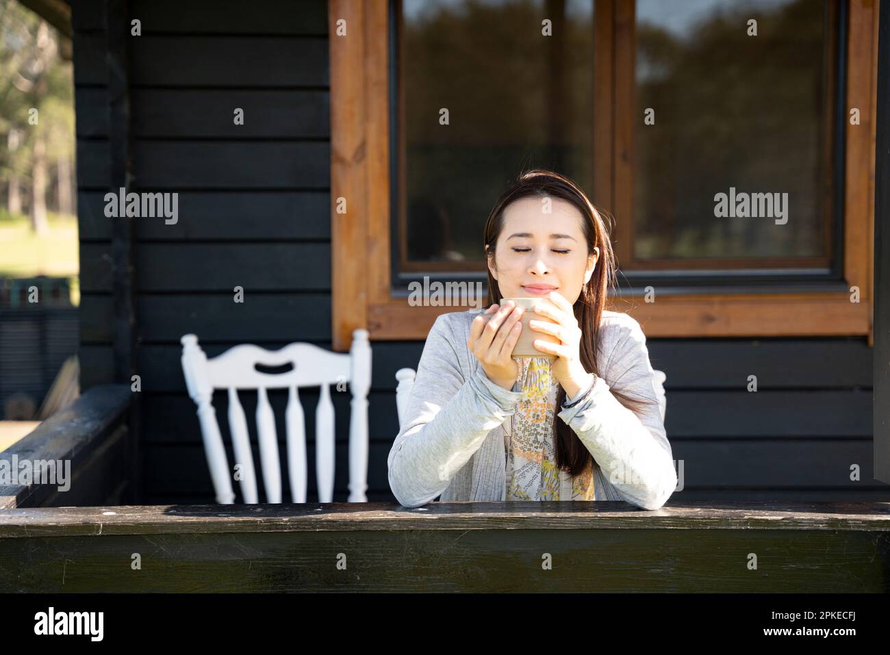 Woman drinking tea on porch of cottage Stock Photo