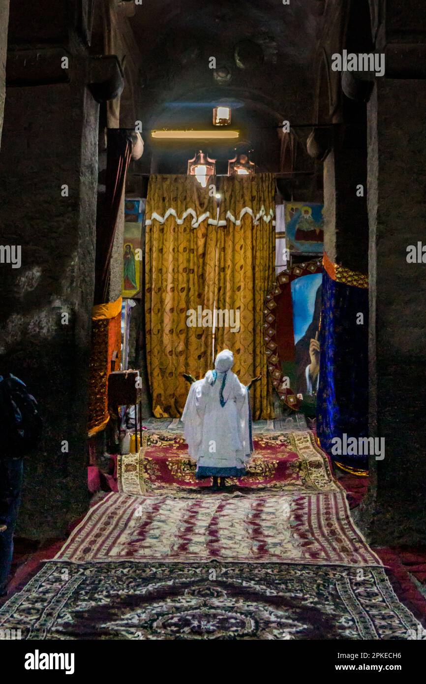 Worshipper praying inside one of the rock hewn temples in Lalibela, Ethiopia during the holy Orthodox Ethiopian Easter celebration of Fasika Stock Photo