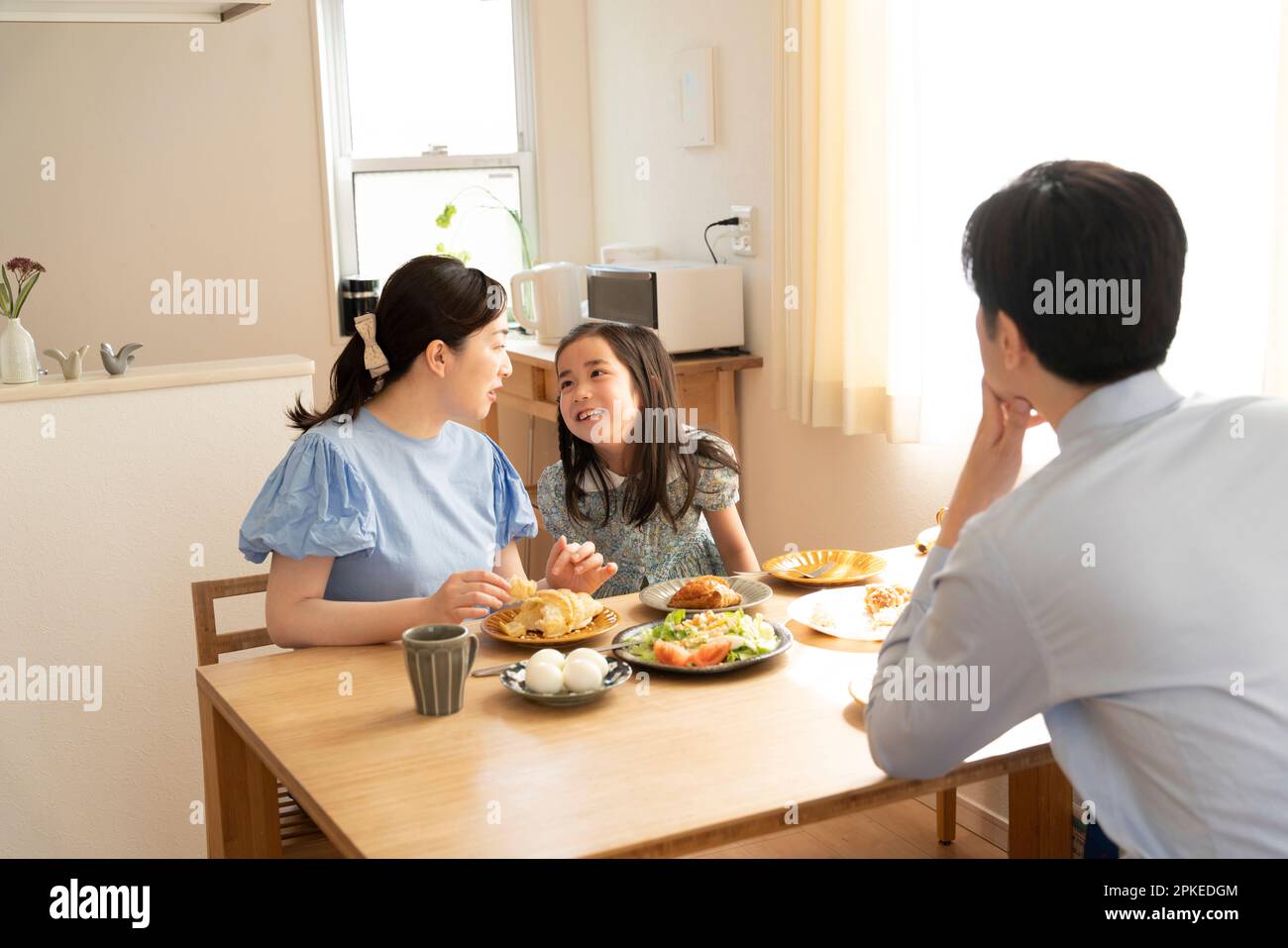 Parents and child eating breakfast while talking Stock Photo