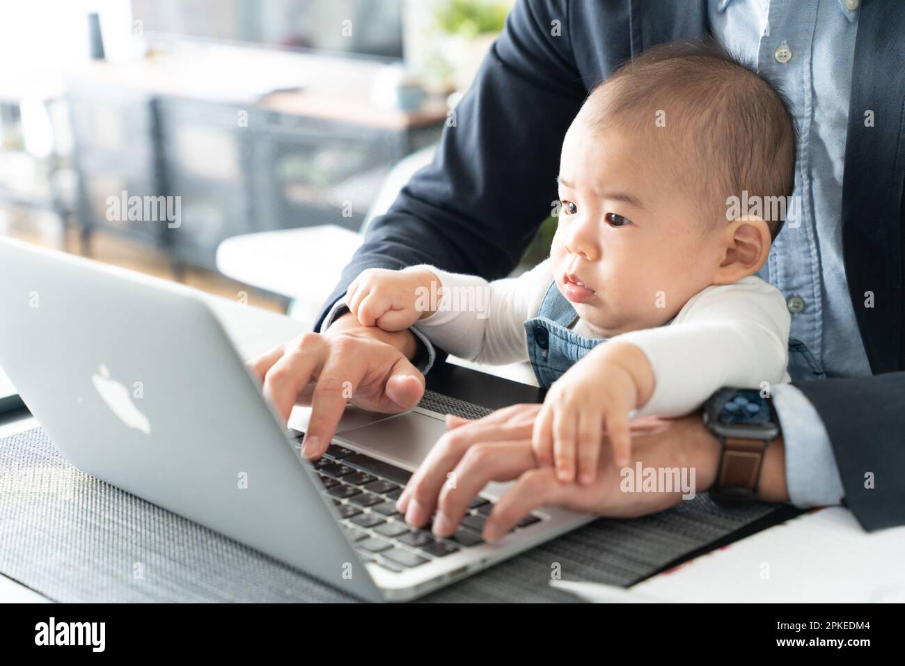 Baby boy looking at computer while being carried by his father Stock Photo