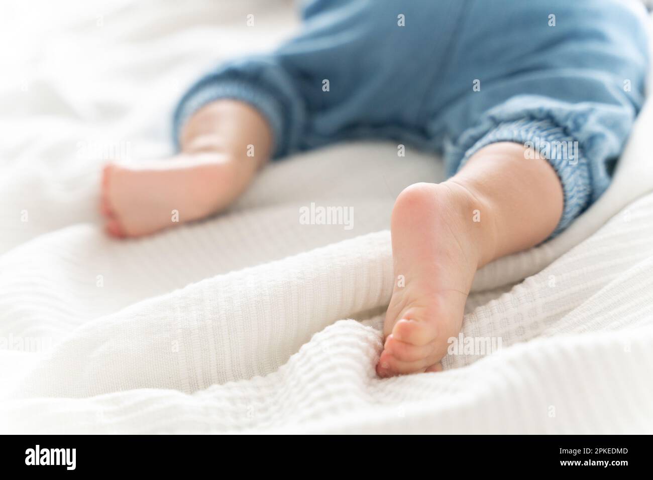 Baby's feet on the sheets, lying on his stomach Stock Photo