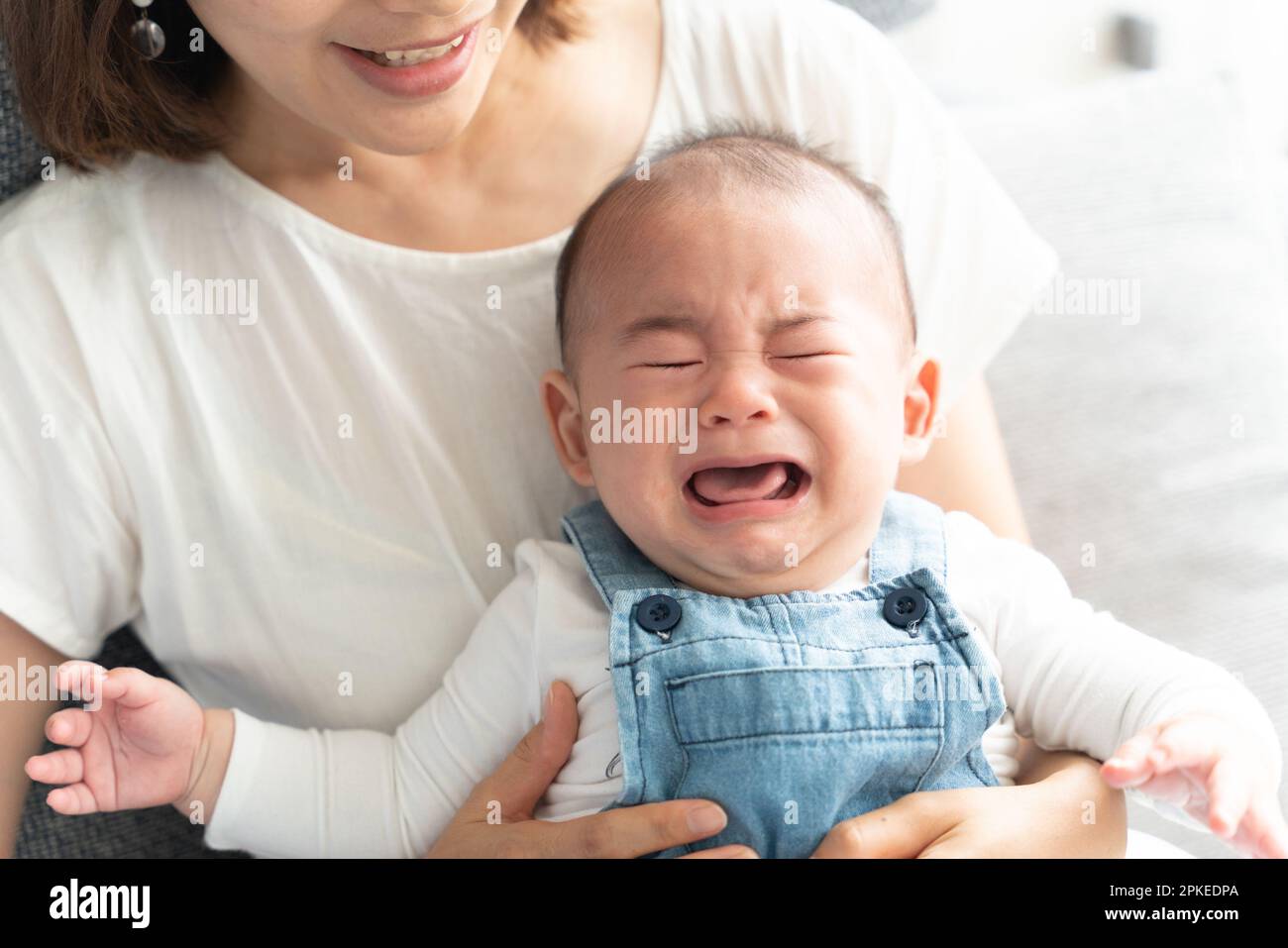 Baby crying in mother's arms Stock Photo