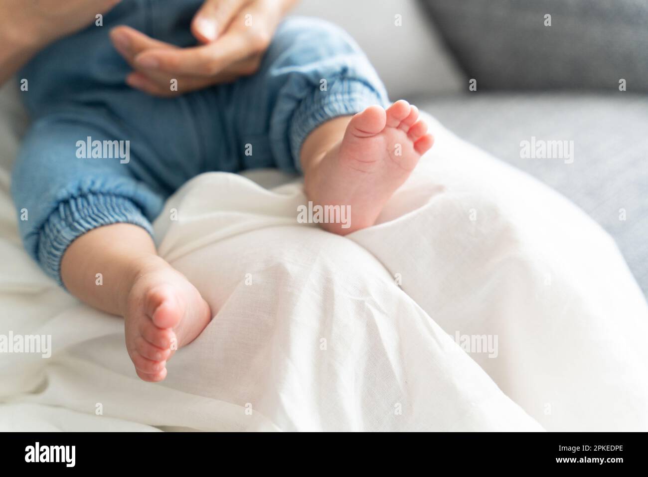 Baby being carried by mother at her feet Stock Photo