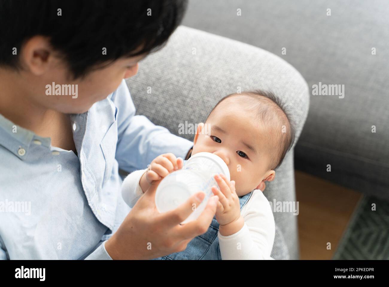 https://c8.alamy.com/comp/2PKEDPR/father-sitting-on-couch-feeding-baby-2PKEDPR.jpg