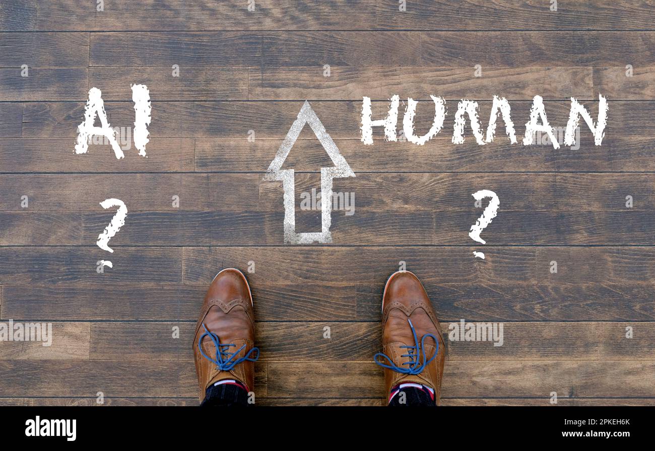 Man looking down at the words Artificial Intelligence - AI - and Human chalked onto the floor Stock Photo