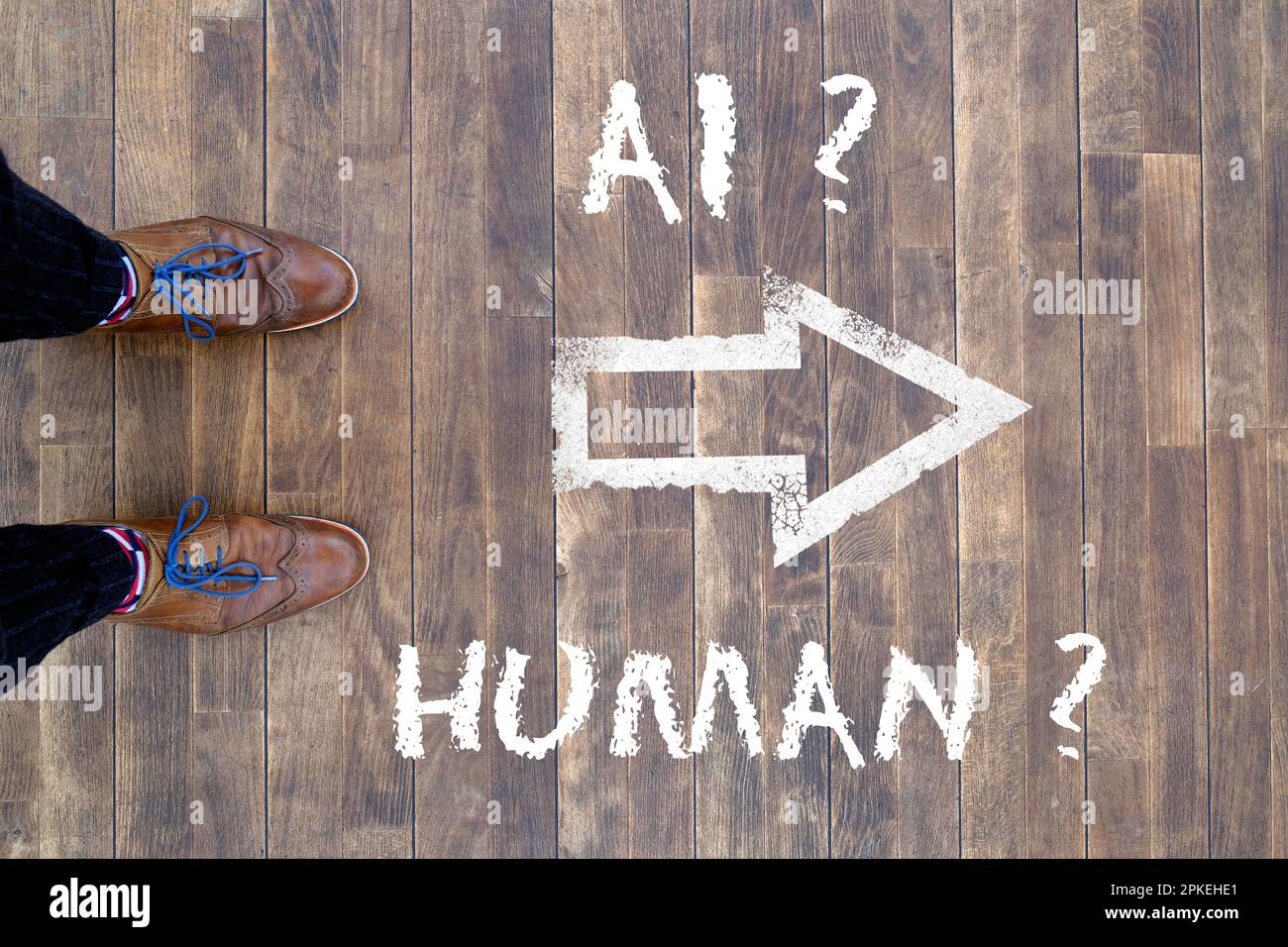 Man looking down at the words Artificial Intelligence - AI - and Human chalked onto the floor Stock Photo