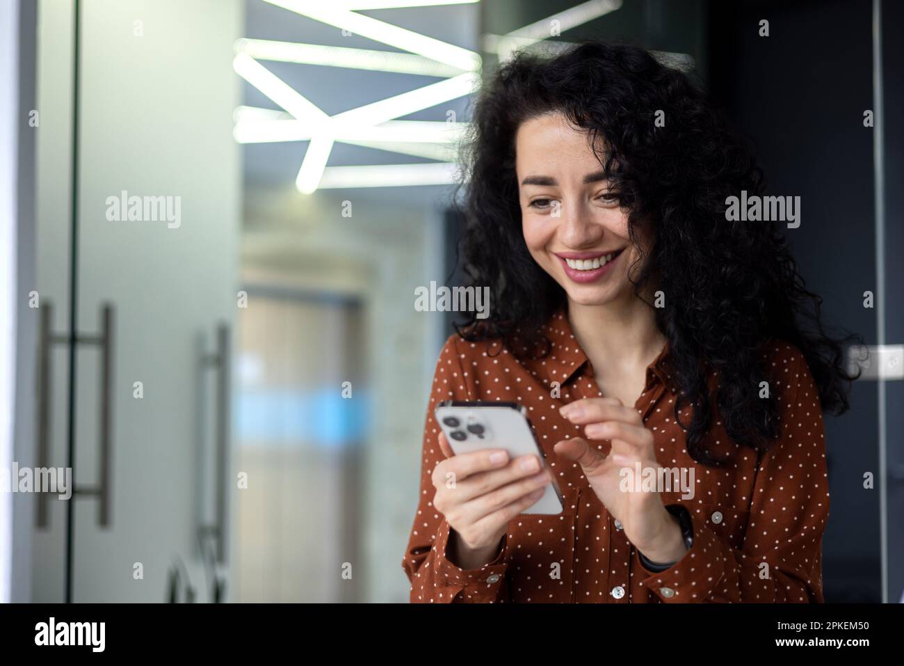Beautiful and successful business woman with curly hair at workplace ...