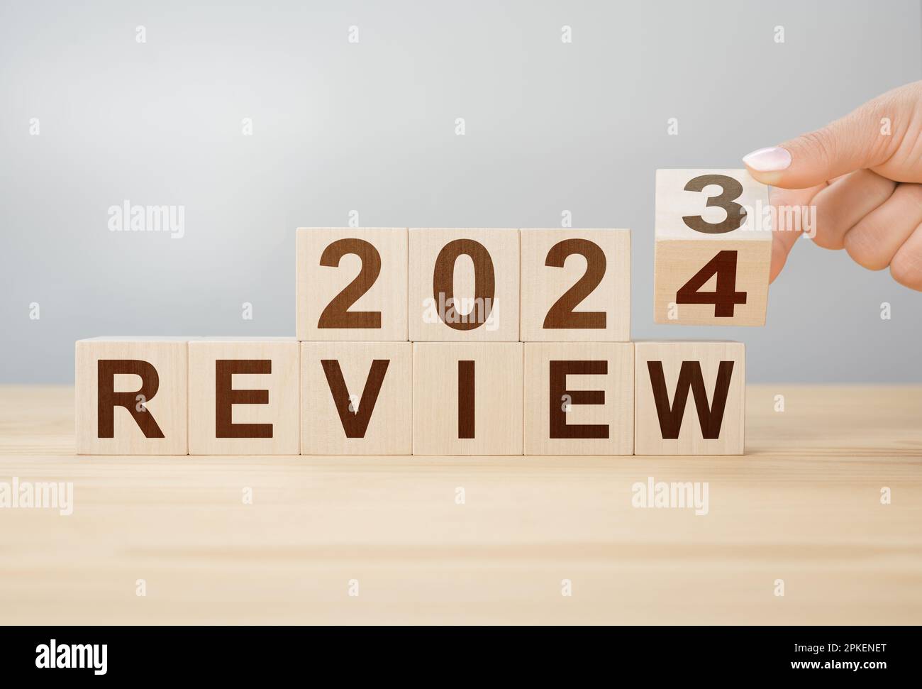 concept of review 2024. hand flips wooden cube and changes words REVIEW