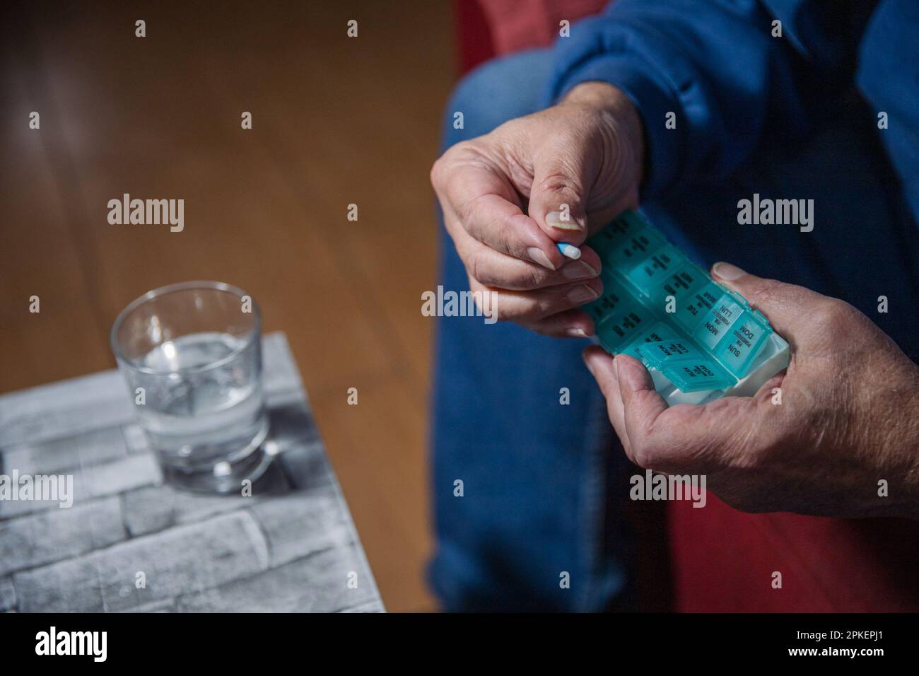 Close-up of an elderly man's hands taking medicines from his medicament dispenser. Stock Photo