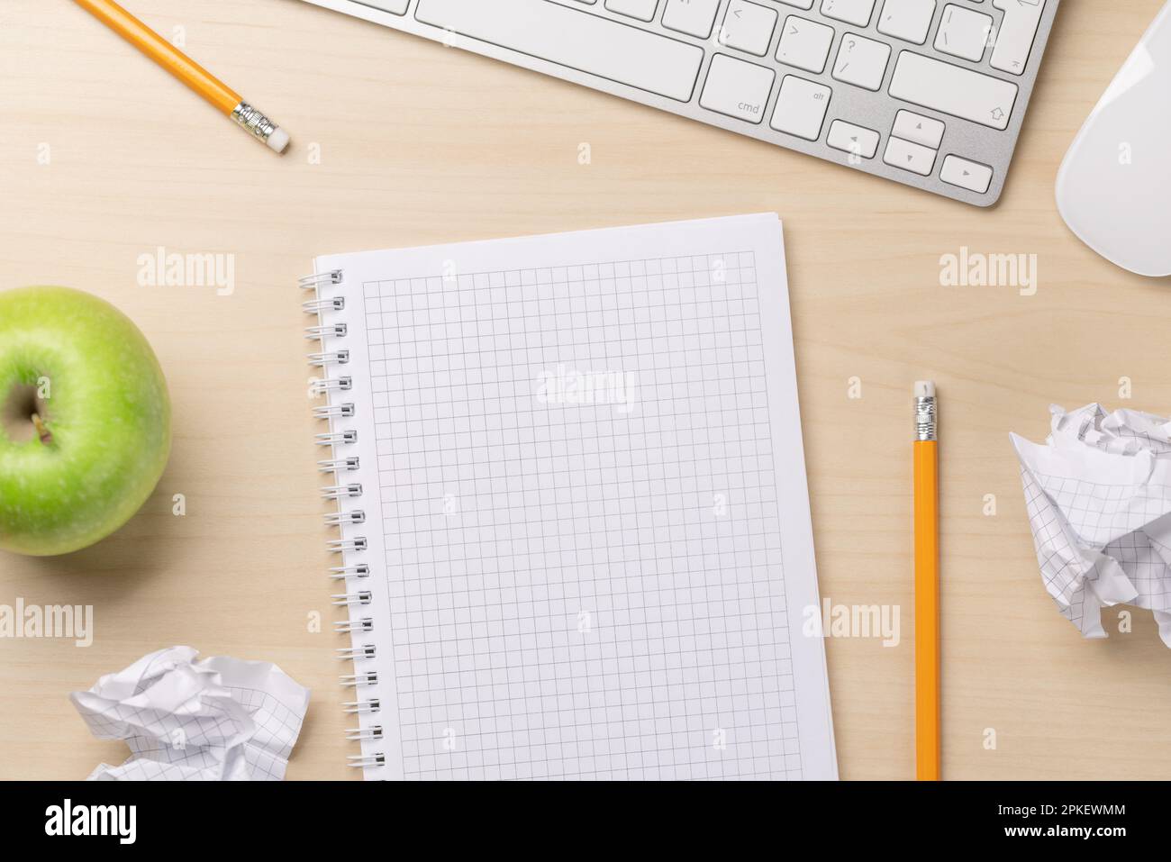 Top view of blank notepad, keyboard, apple and crumpled papers on desk ...