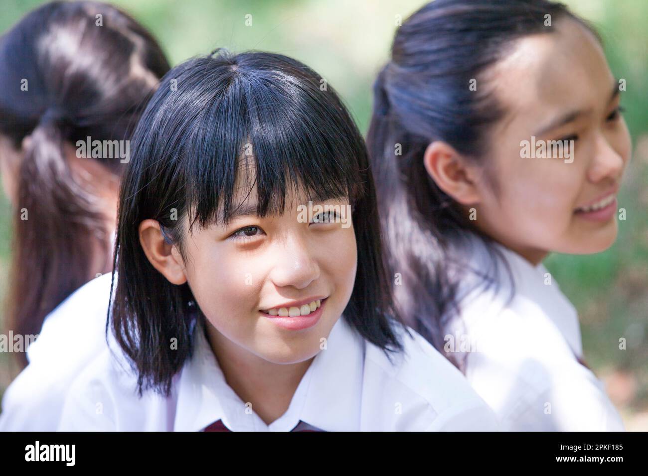 Junior high school students sitting back to back in a field Stock Photo ...