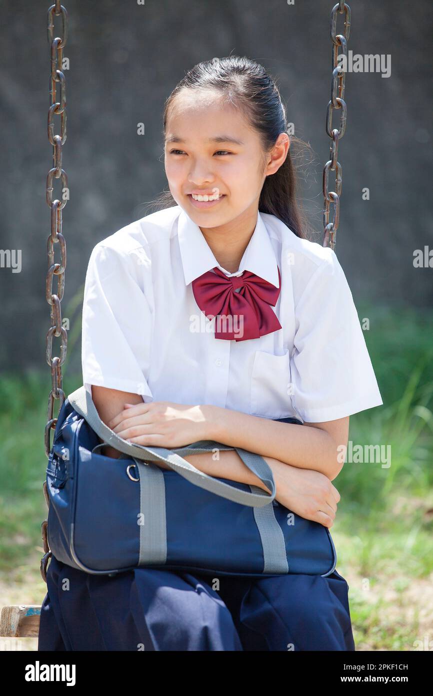 Junior high school students sitting on a swing Stock Photo Alamy