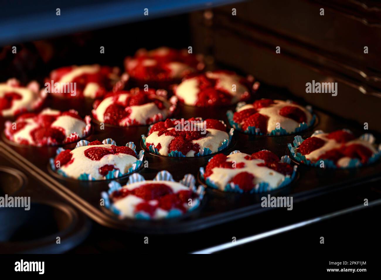 Himbeermuffins in einer Muffins Backform, backen in einem Ofen Stock Photo