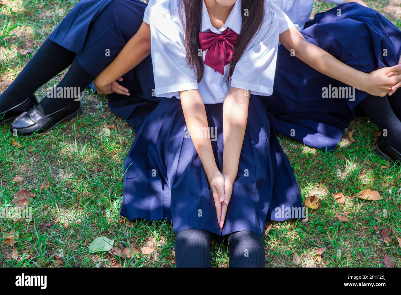 Junior high school students sitting back to back on the grass Stock ...