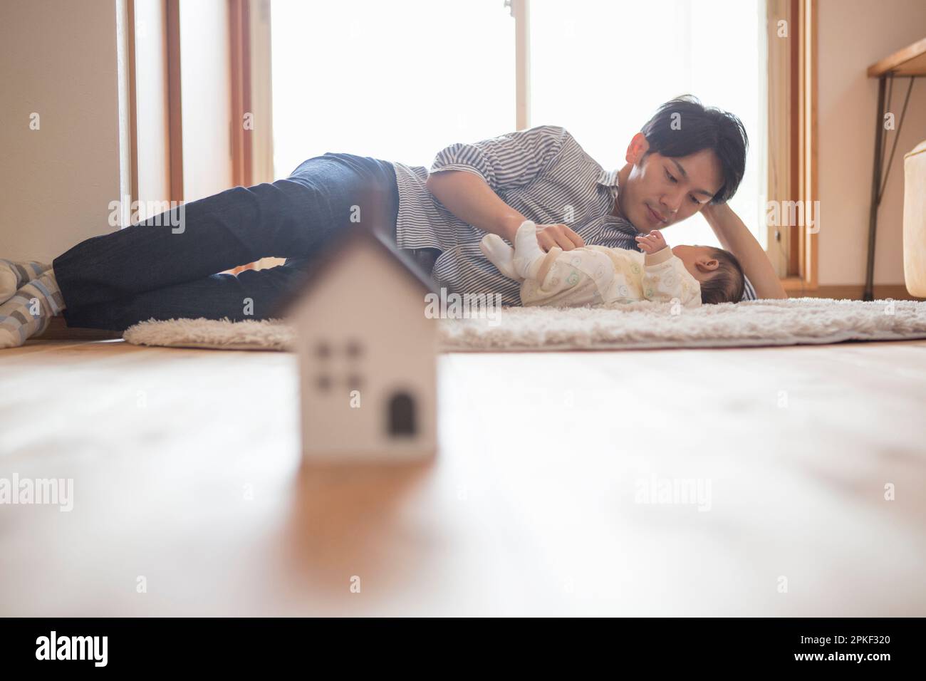 Model of a house with a father taking care of a child Stock Photo