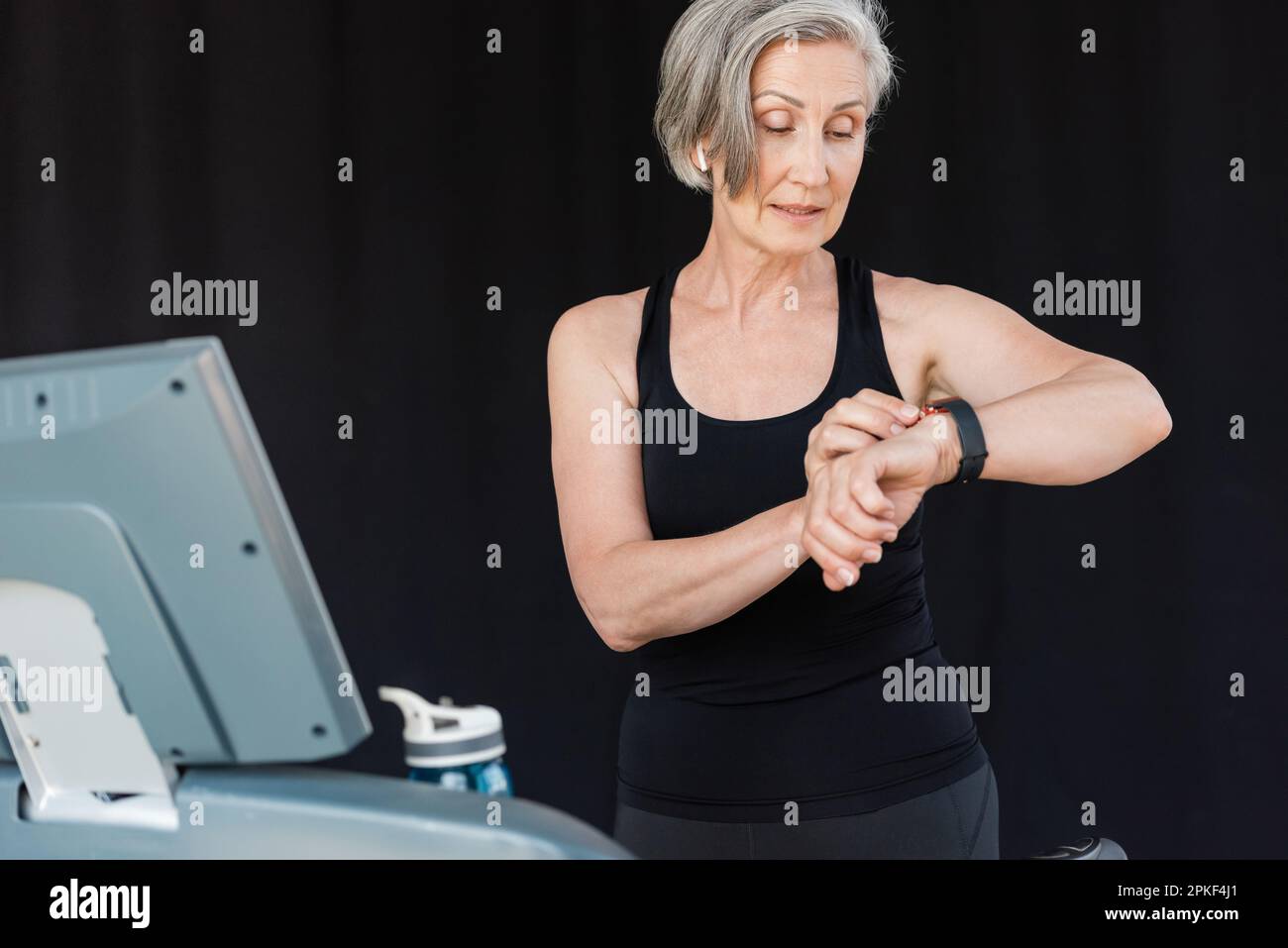 senior woman with grey hair checking activity on fitness tracker after ...