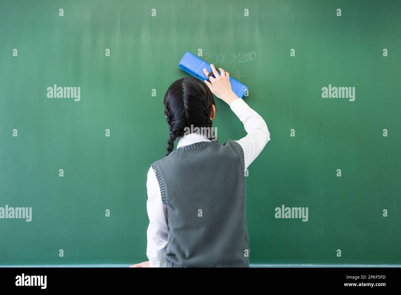 Junior high school girls writing with chalk on the blackboard Stock