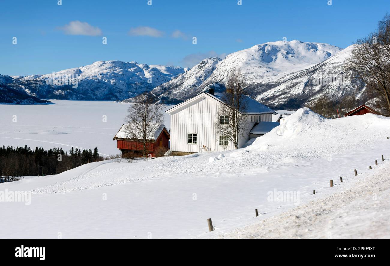 The settlement Midtgarden close to Raulandsgrend (Vestfold and Telemark), Norway with the frozen lake Totak and the mountains Breiddalseggi (1563 m) a Stock Photo