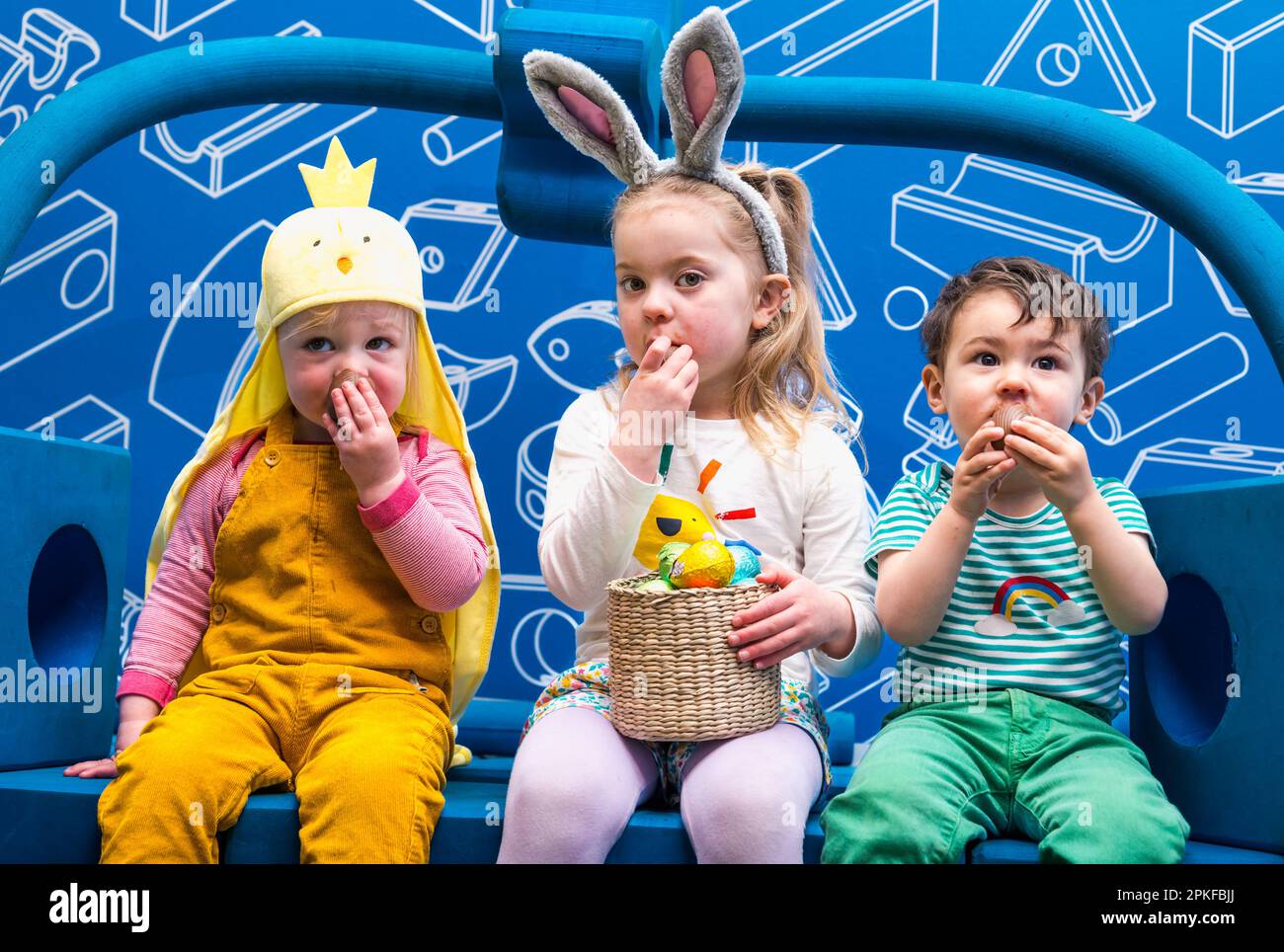 Three young children eating chocolate Easter eggs at Edinburgh Science Festival, Scotland, UK Stock Photo