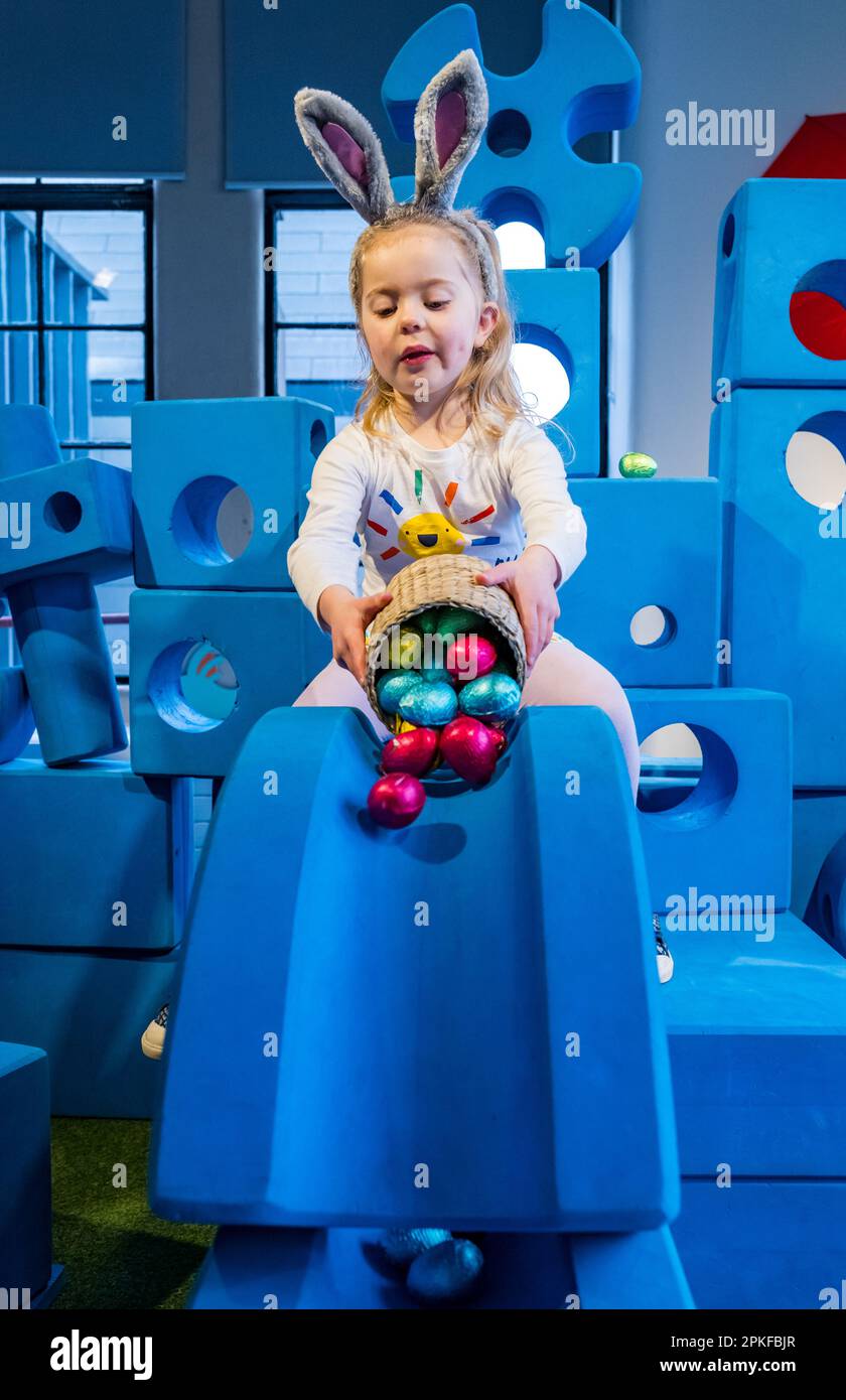 Young girl having fun rolling chocolate Easter eggs down slide, Edinburgh Science Festival, Scotland, UK Stock Photo