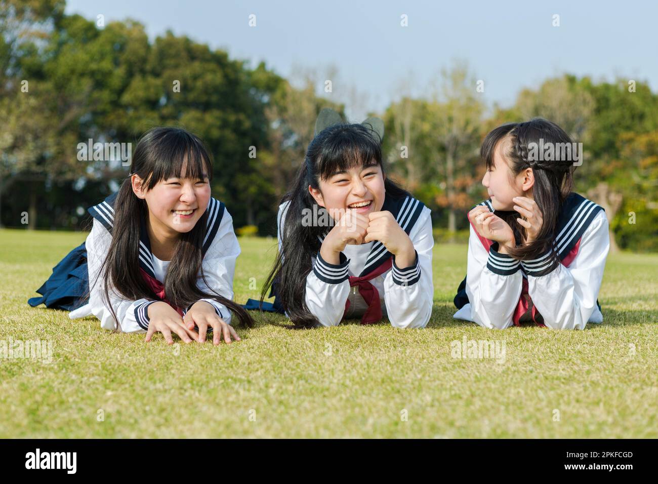 Schoolgirls lying on the grass talking to each other Stock Photo
