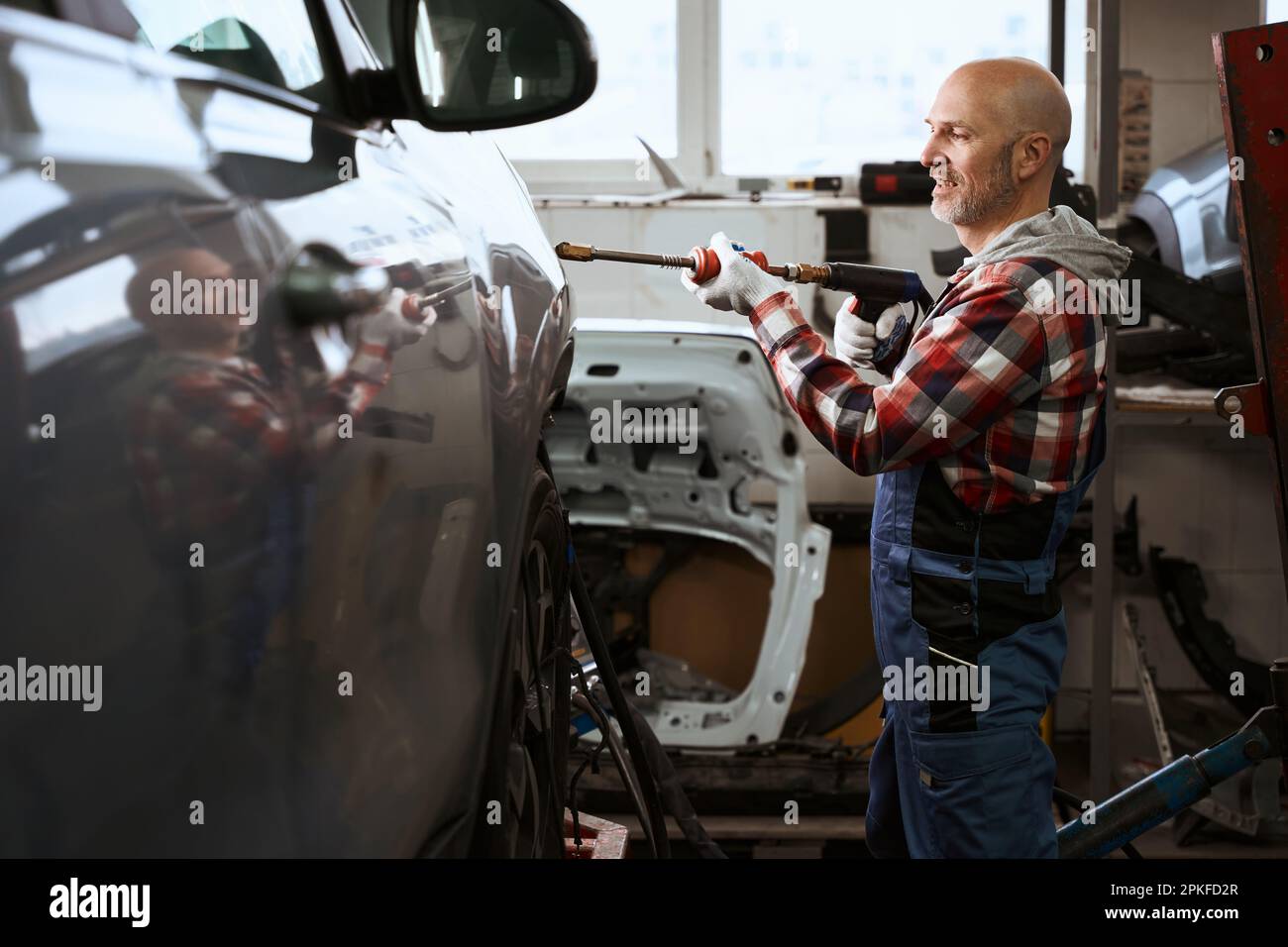 Auto repairman uses spotter to repair car Stock Photo