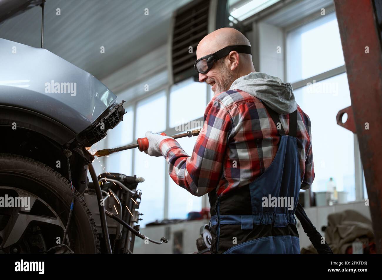 Auto repairman in goggles repairing a car after an accident Stock Photo
