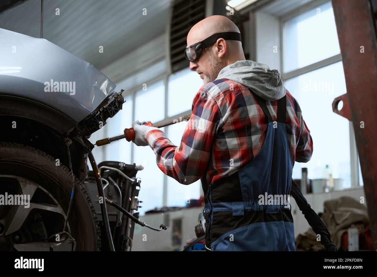 Auto repairman in protective glasses works spotter for car repair Stock Photo