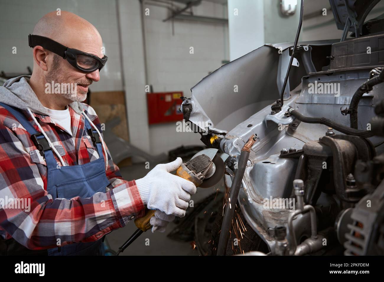 Auto mechanic in goggles uses pneumatic cutter Stock Photo