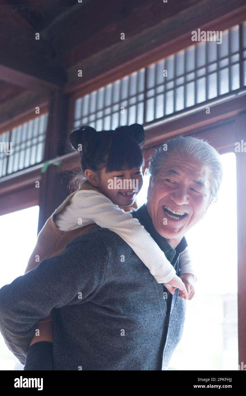 Senior man and his grandson giving a piggyback ride in a country house Stock Photo